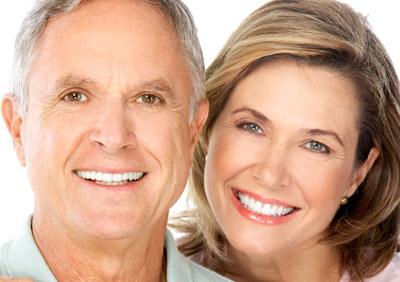 An older man and woman posing together for a photo with smiles on their faces.